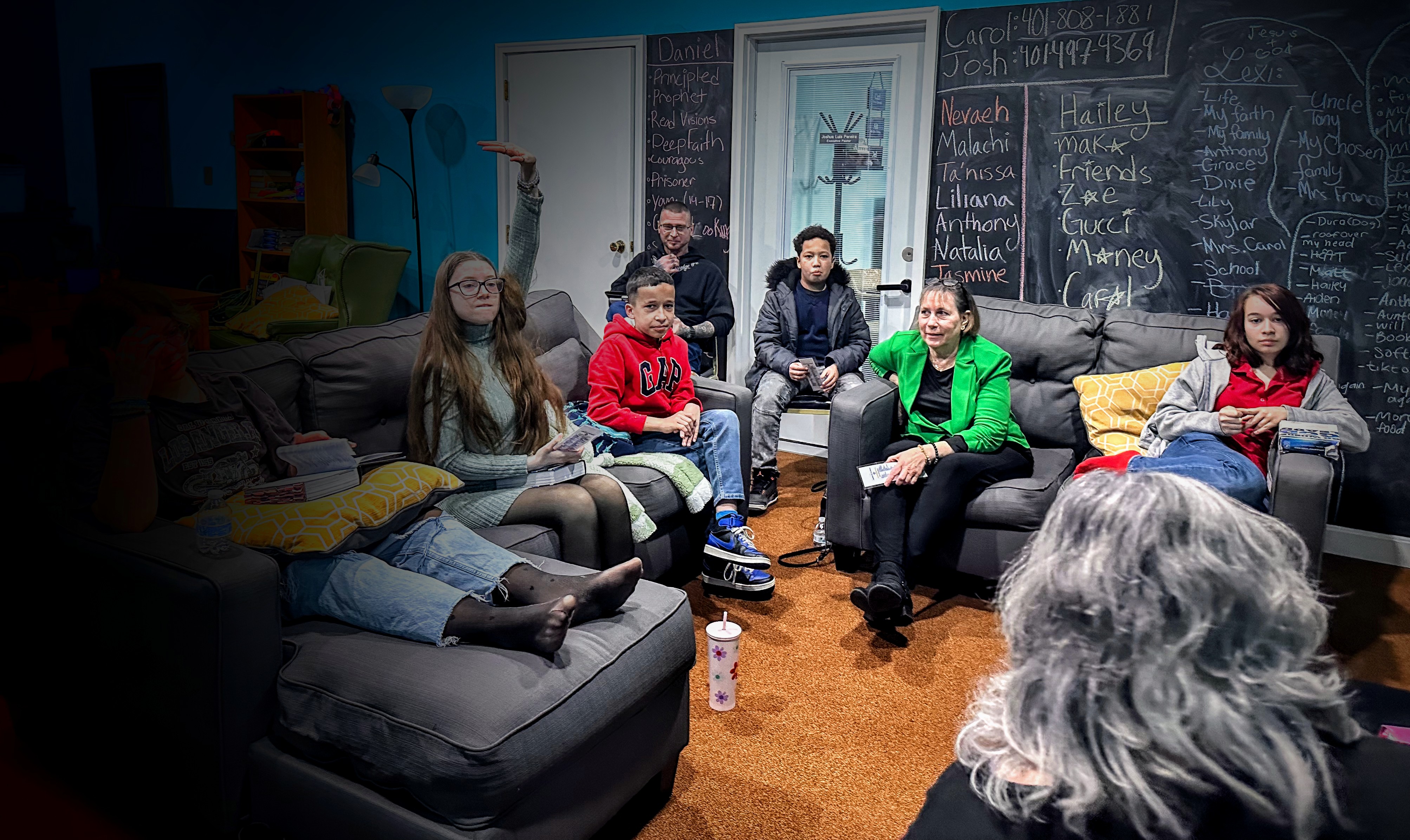 Project137 youth ministry gathering with teens and leaders in comfortable youth center setting with chalkboard wall showing member names