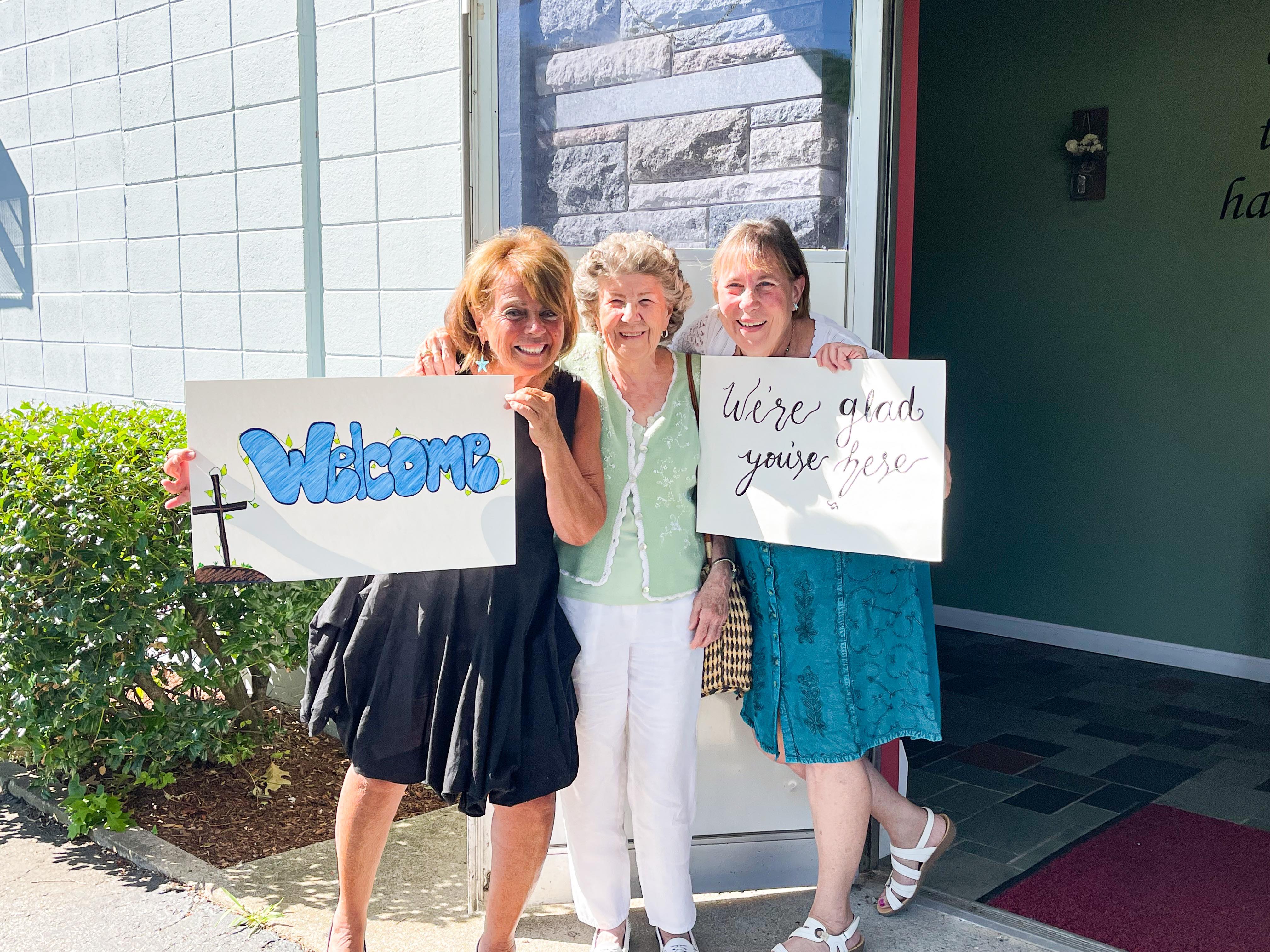 Welcoming church members holding welcome signs